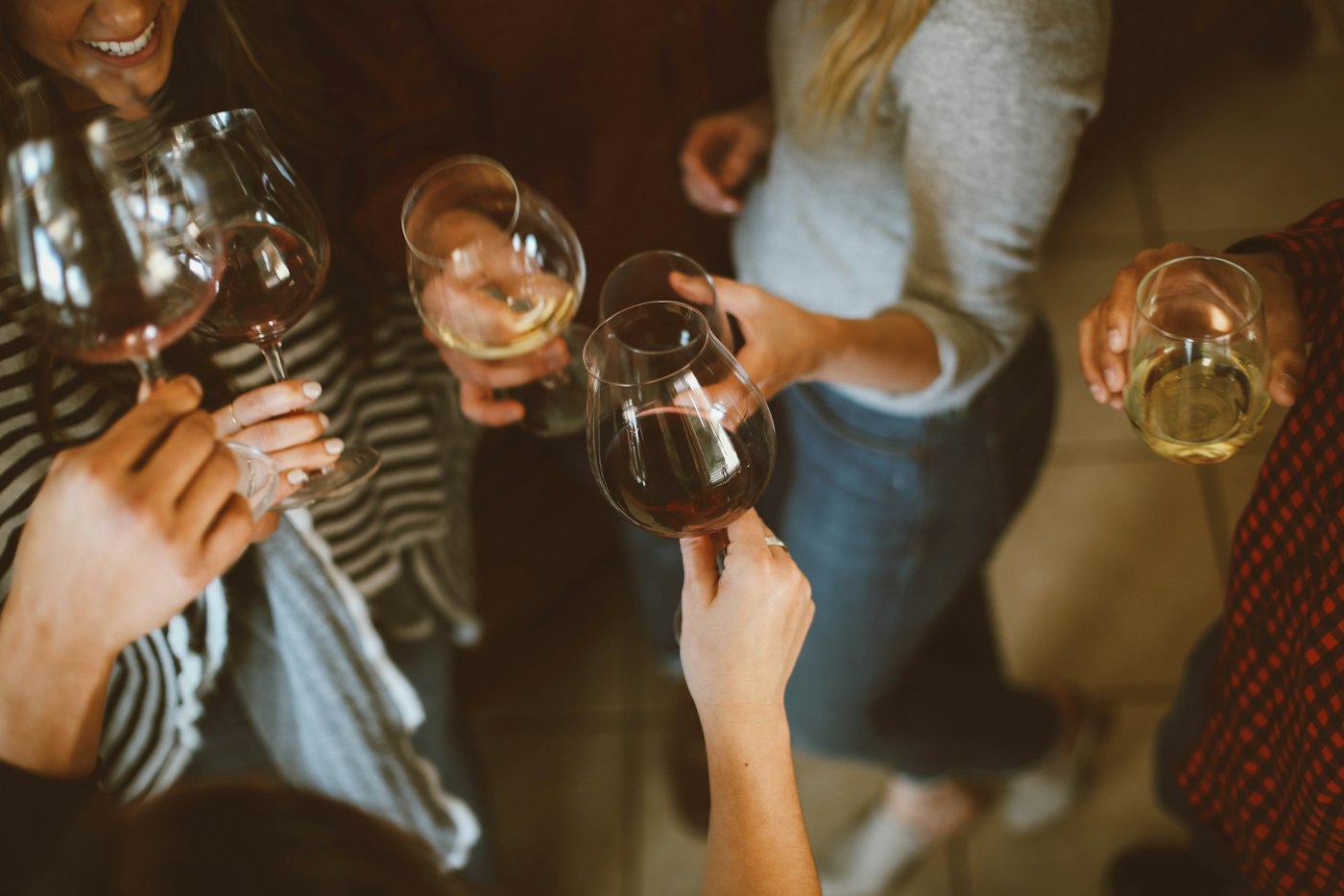 A group of friends tossing back wine glasses in celebration